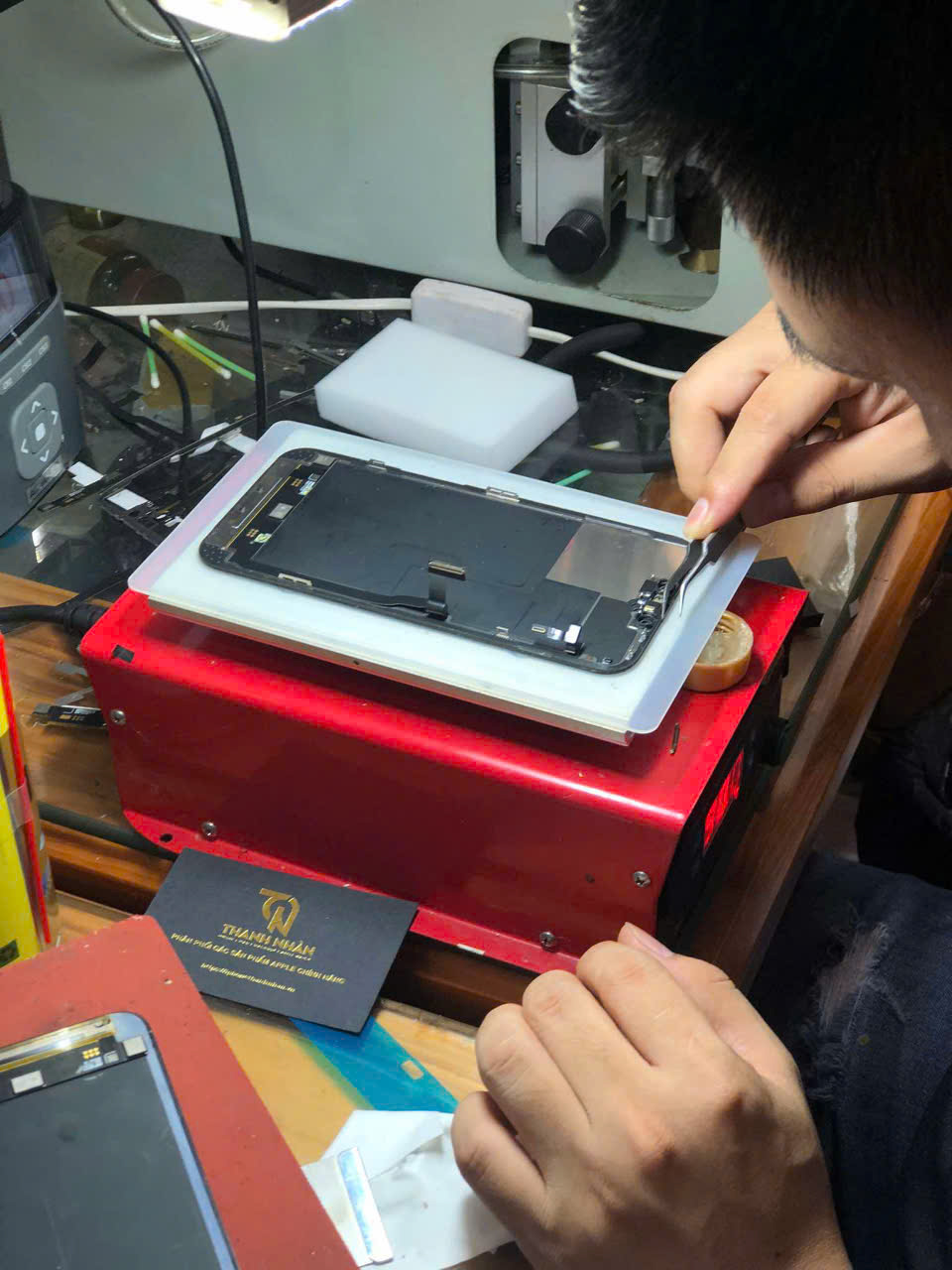 Kỹ thuật viên đang thao tác ép kính tại Thanh Nhàn Apple bằng công nghệ ép lạnh – giữ nguyên cảm ứng gốc.